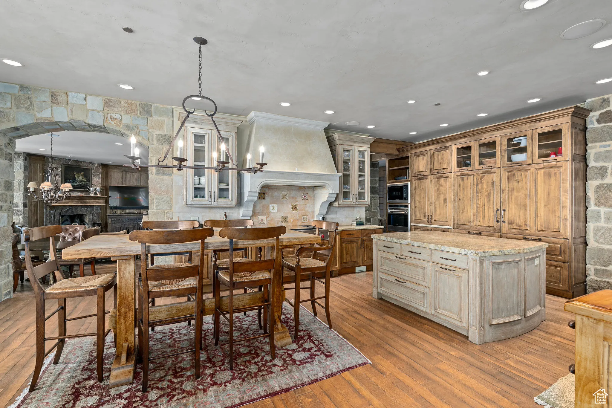 Dining area with arched walkways, recessed lighting, an inviting chandelier, light wood-style floors, and a large fireplace