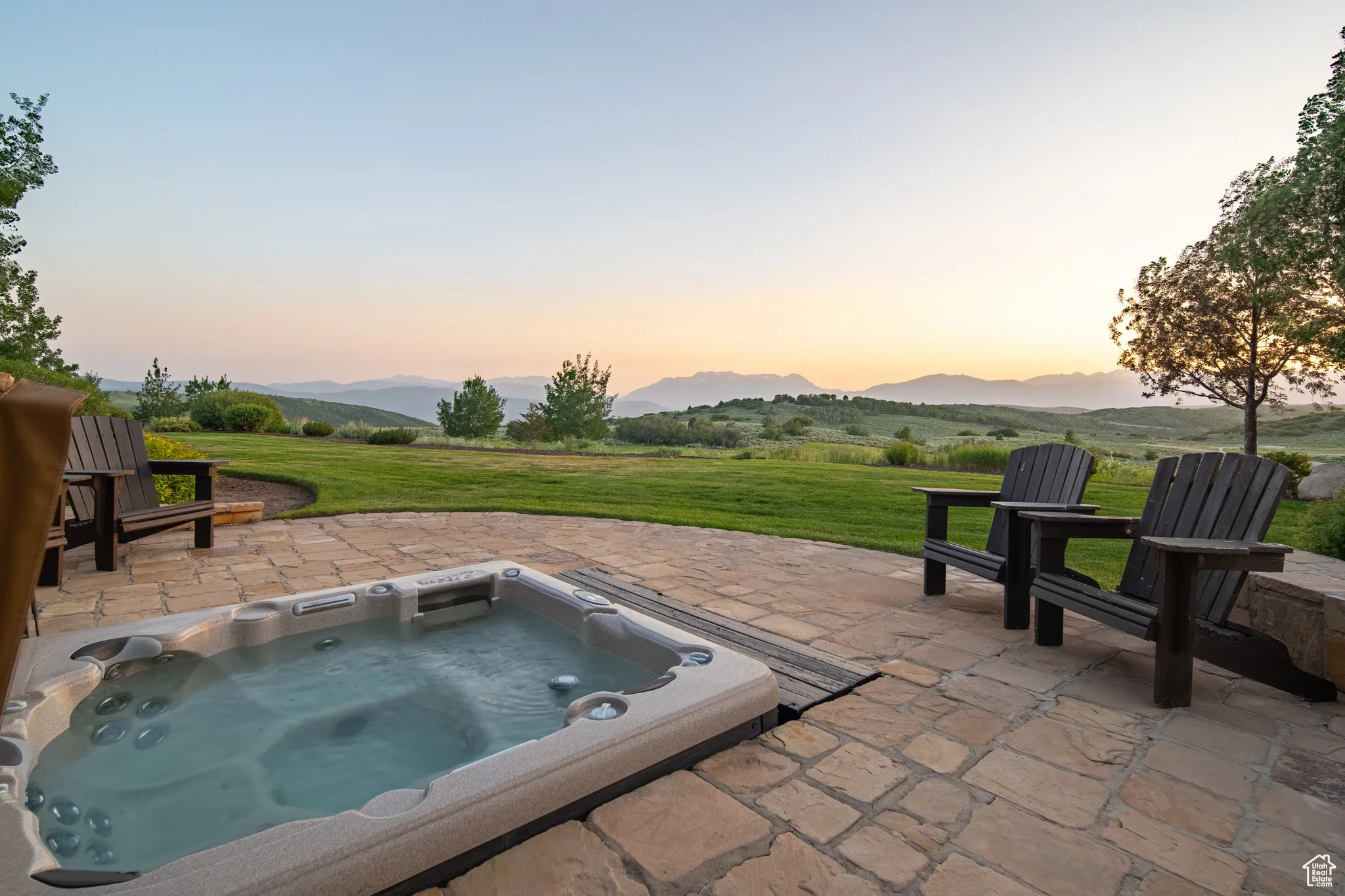 Patio terrace at dusk featuring a patio, an outdoor hot tub, and a mountain view