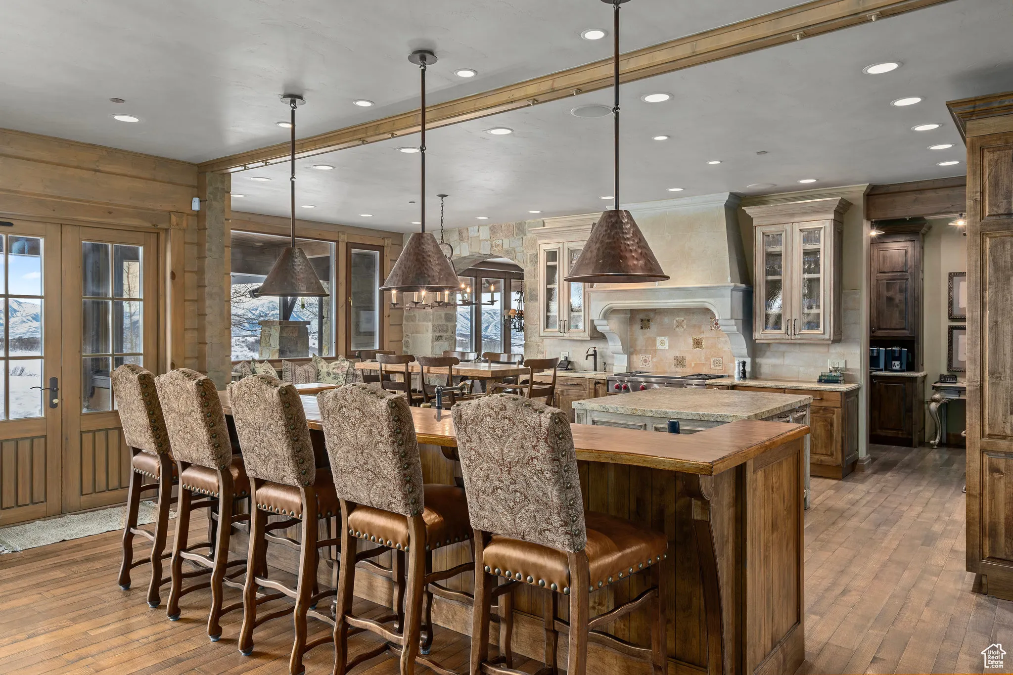 Kitchen with french doors, a large island, light countertops, premium range hood, and a kitchen breakfast bar