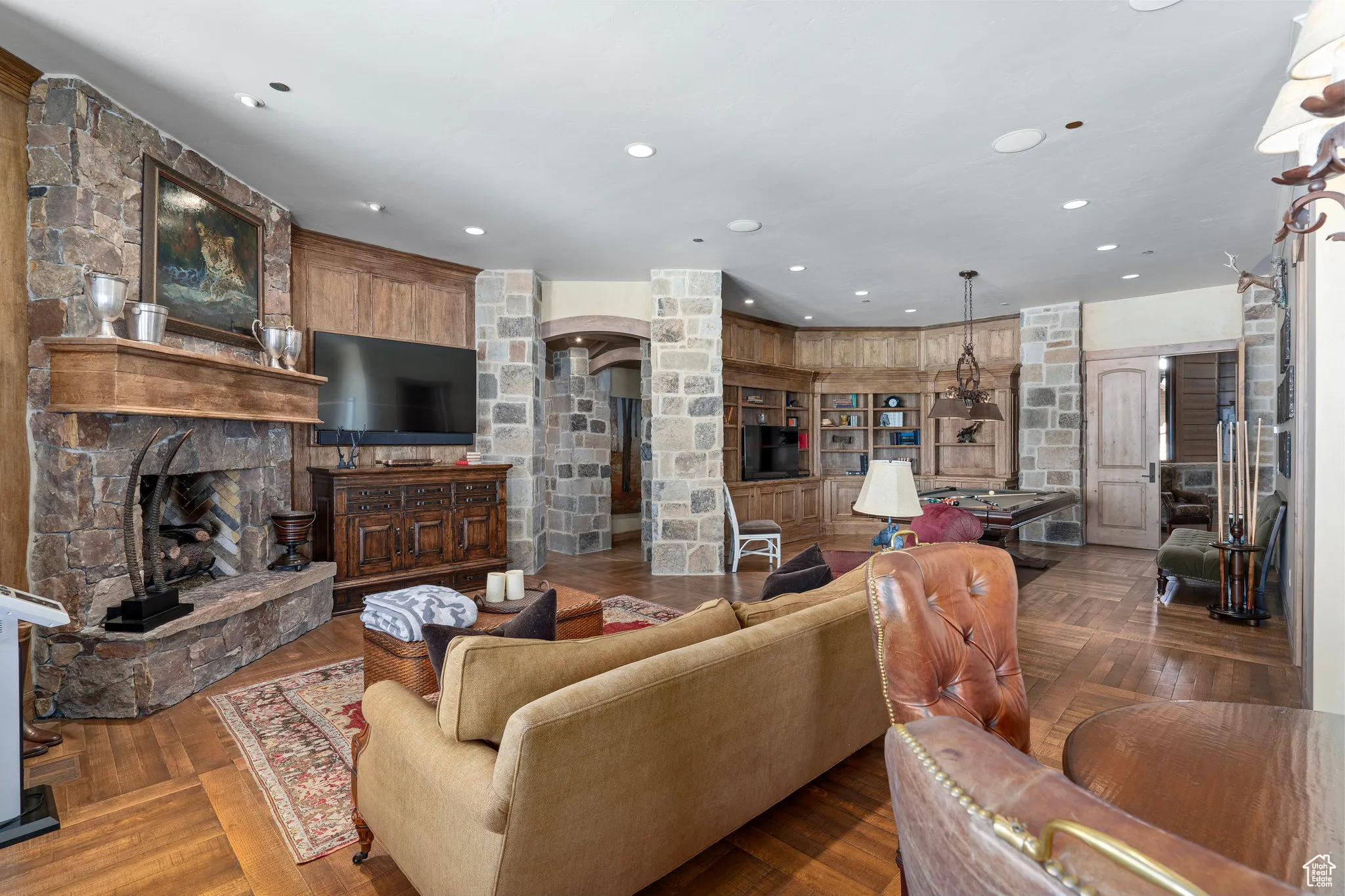 Living room featuring arched walkways, wood finished floors, a stone fireplace, and recessed lighting