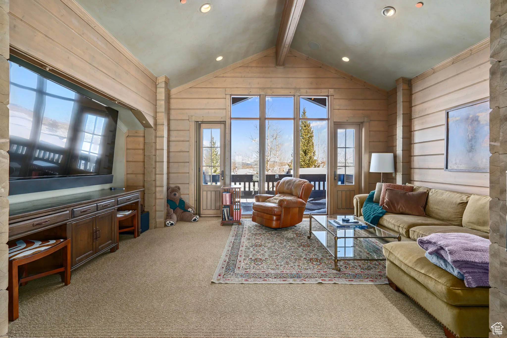 Carpeted living area featuring lofted ceiling with beams, wood walls, and recessed lighting