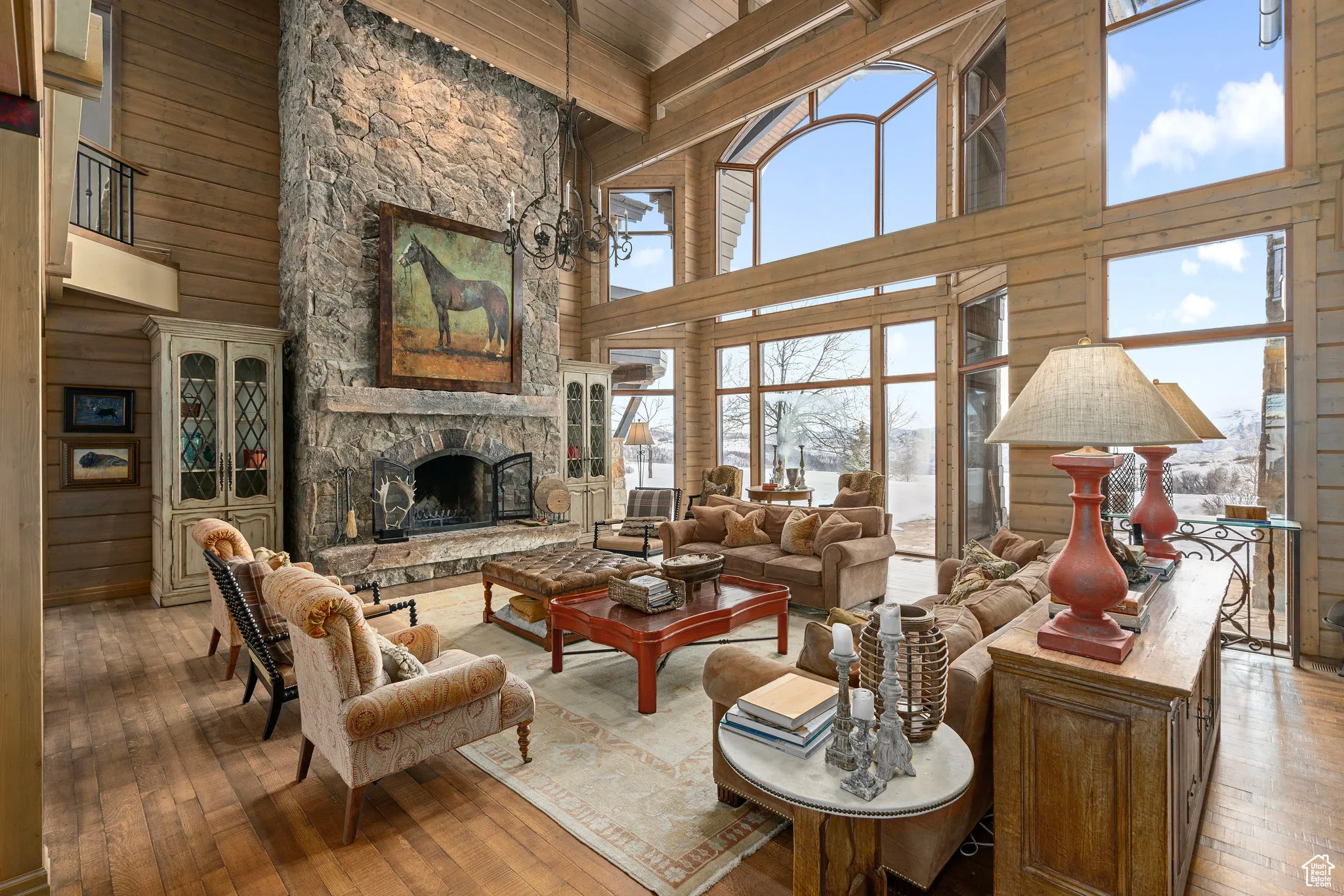 Living area with a chandelier, a stone fireplace, hardwood / wood-style flooring, wooden walls, and beam ceiling