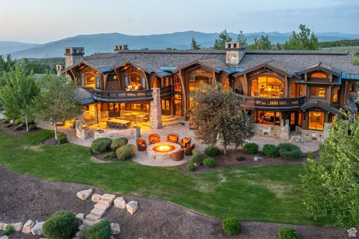 Rear view of property featuring an outdoor fire pit, a balcony, a patio, a chimney, and a mountain view