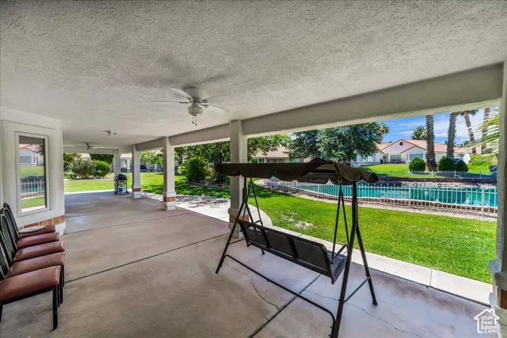 Spacious covered patio featuring ceiling fans, concrete flooring, and decorative column bases