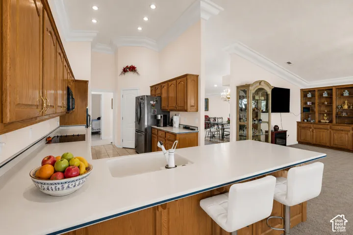 Kitchen island with integrated sink and seating for two, wood-finish cabinetry, recessed lighting, and stainless steel appliances