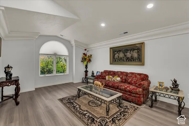 Spacious living area featuring wood-finish flooring, recessed lighting, and a large arched window