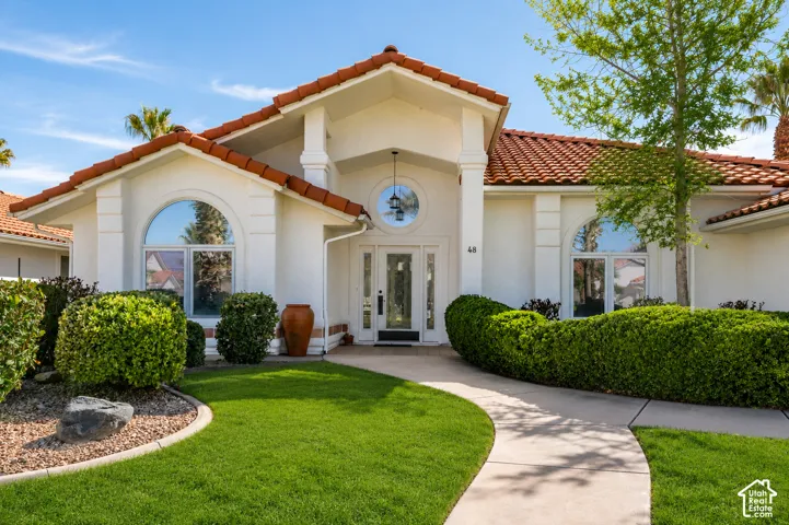Stucco exterior with a terracotta tile roof, featuring an arched entry and a curved concrete pathway