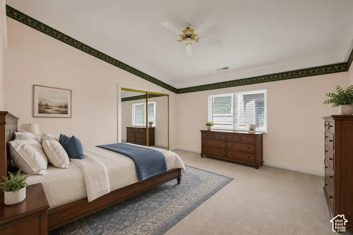 Vaulted ceiling room featuring carpet flooring, natural light through a double window, and a ceiling fan