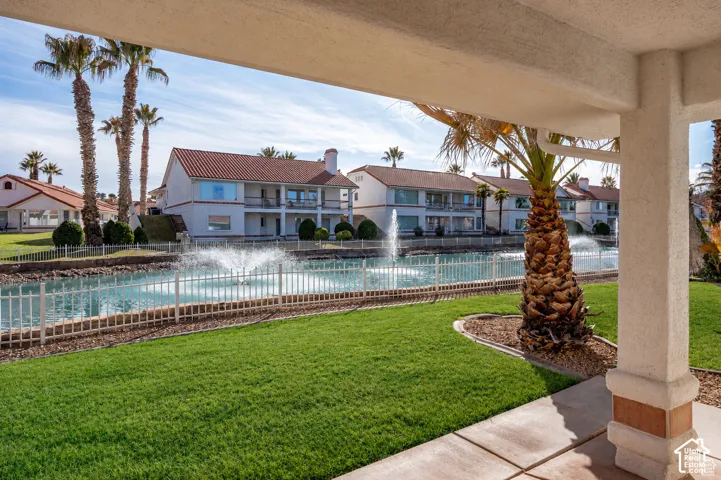 Lush green lawn with a palm tree, concrete patio, and a columned stucco exterior