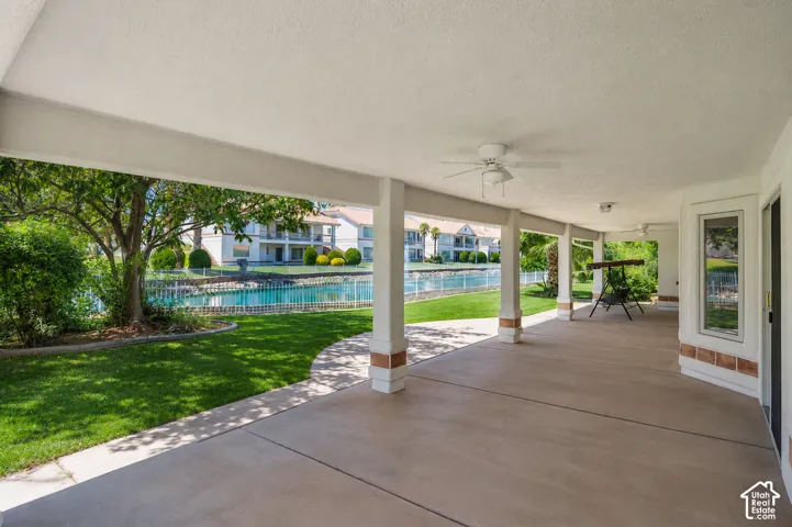 Expansive covered patio featuring a concrete surface, multiple ceiling fans, and structural columns with brick accents