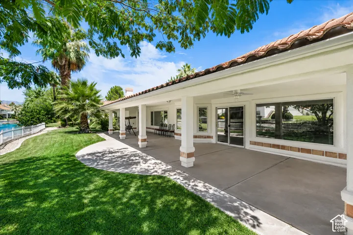 Expansive covered patio featuring a concrete surface, decorative brick accents on columns, and multiple sliding glass doors