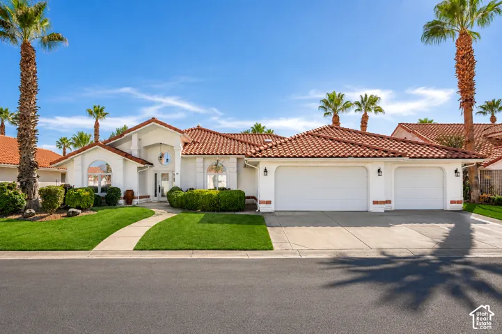 Mediterranean-style exterior featuring a tile roof, stucco finish, and a three-car garage