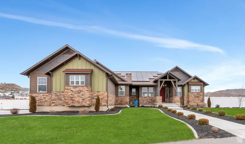 Craftsman-style house featuring solar panels, board and batten siding, a mountain view, and stone siding