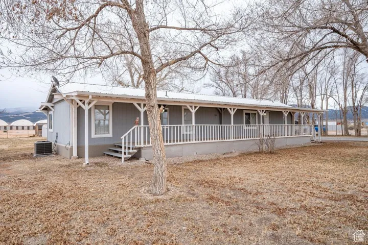 View of front of home featuring a porch, metal roof, and central air condition unit