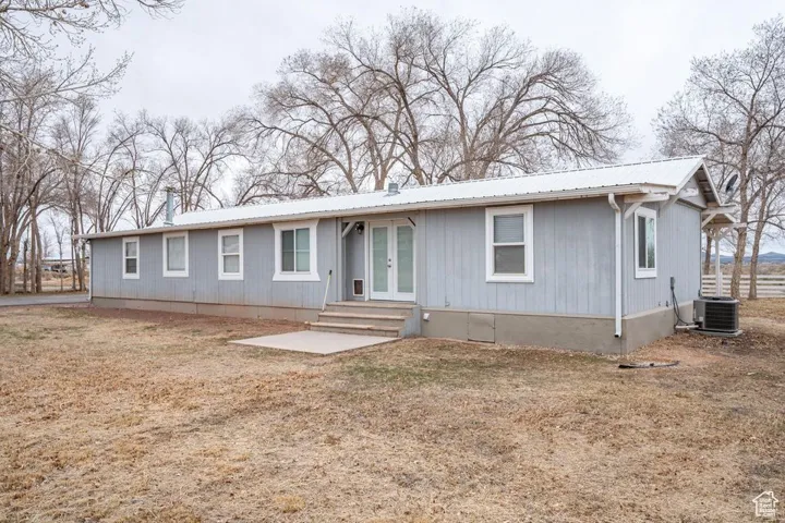 View of front of home with entry steps, metal roof, french doors, and cooling unit