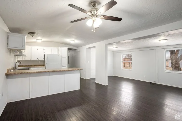 Kitchen featuring freestanding refrigerator, a sink, a peninsula, plenty of natural light, and under cabinet range hood
