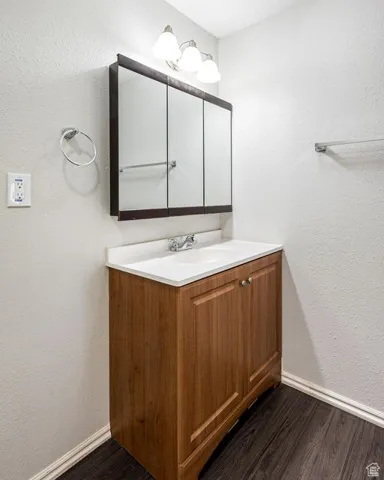 Bathroom with baseboards, wood finished floors, and vanity