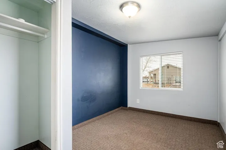 Unfurnished bedroom with a textured ceiling, carpet, and baseboards