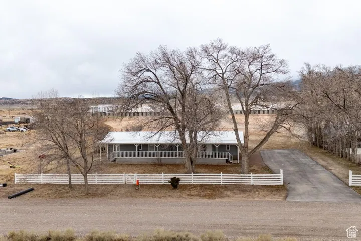 View of front facade with a fenced front yard, covered porch, and driveway
