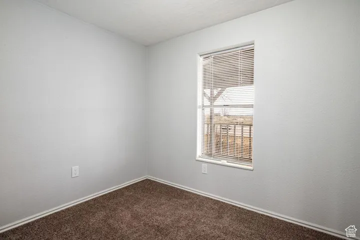 Unfurnished room with dark carpet and baseboards