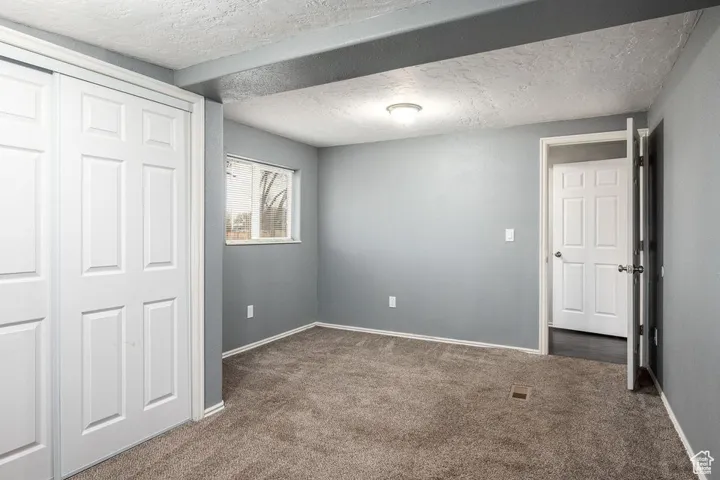 Unfurnished bedroom featuring carpet floors, a closet, baseboards, and a textured ceiling