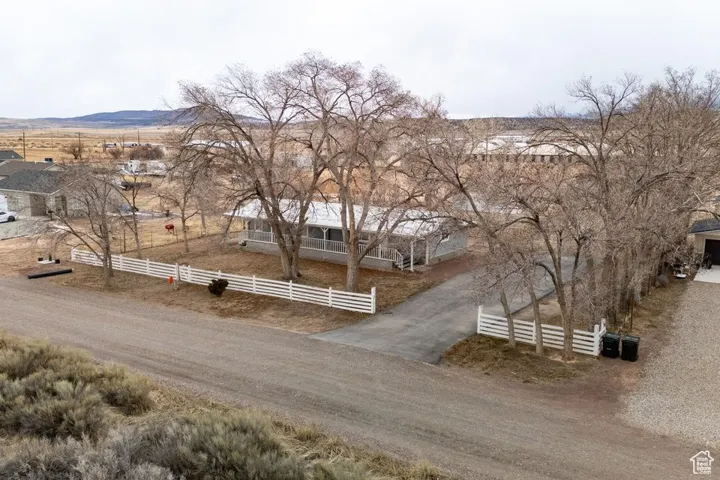 Exterior space featuring a fenced front yard, a rural view, a mountain view, and dirt driveway