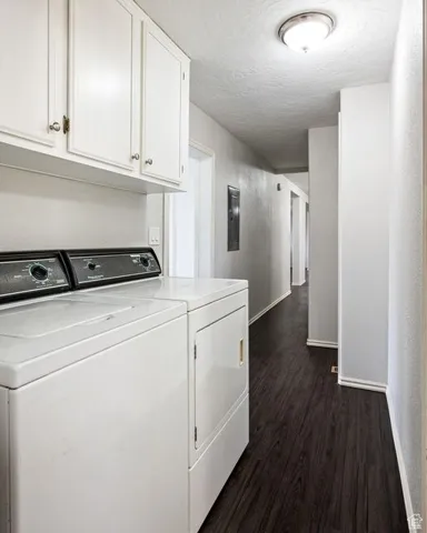 Laundry area with dark wood-style floors, separate washer and dryer, a textured ceiling, and cabinet space