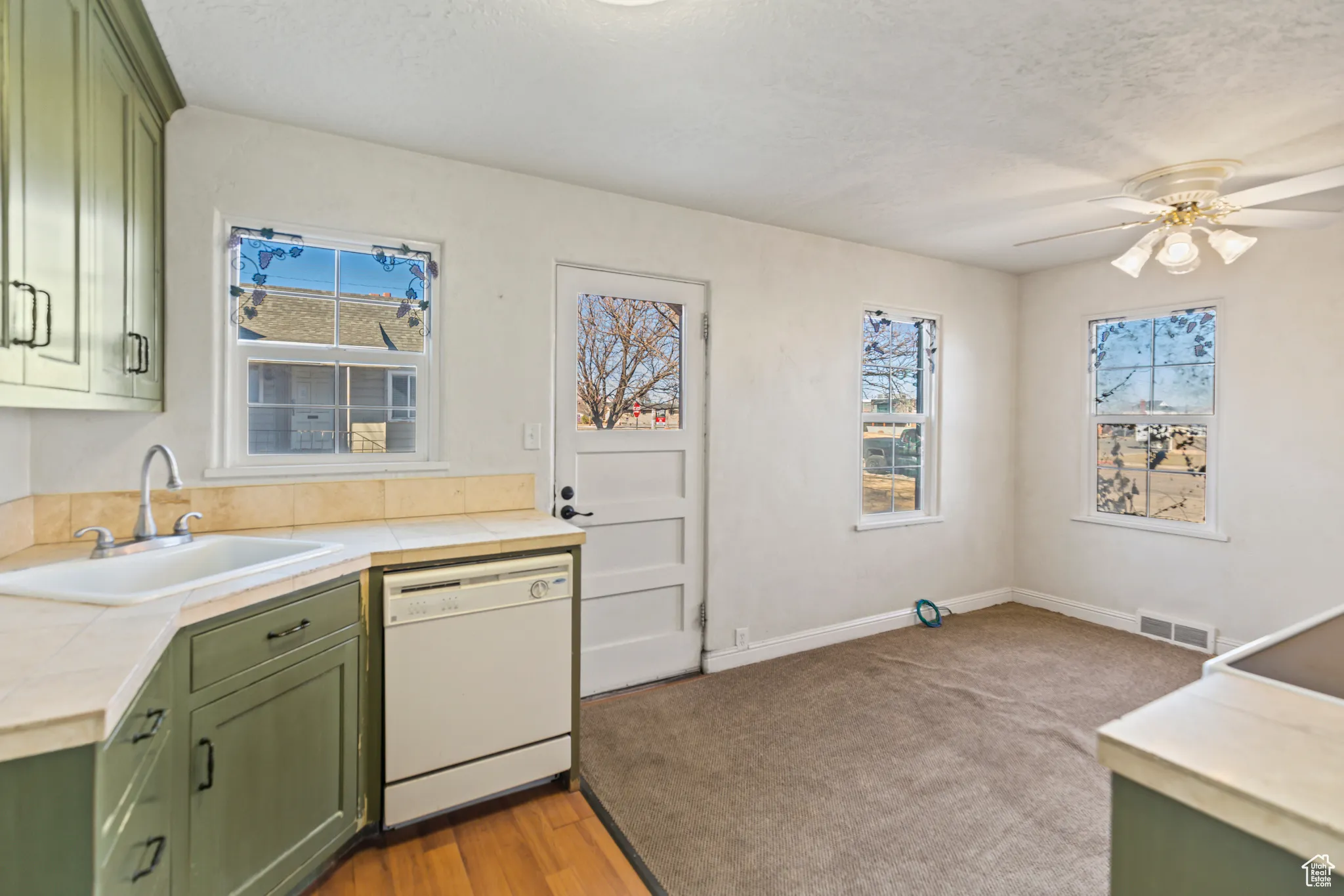 Kitchen with dishwasher, a sink, visible vents, and green cabinetry