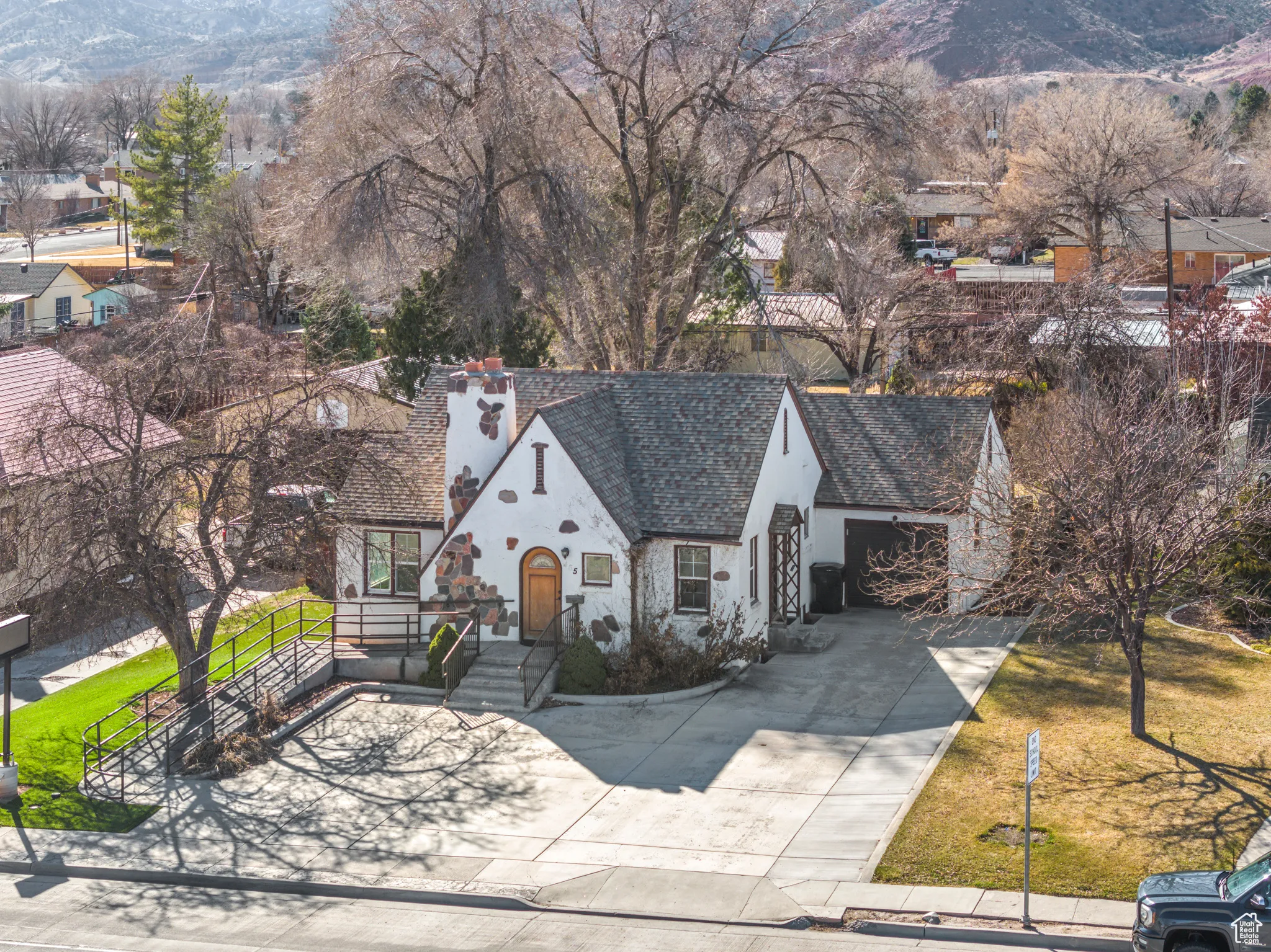 View of front of property with concrete driveway, a mountain view, roof with shingles, and stucco siding