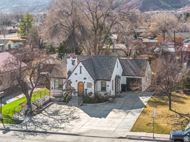 View of front of property with concrete driveway, a mountain view, roof with shingles, and stucco siding