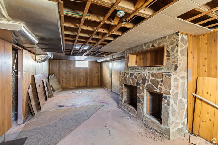 Basement with a stone fireplace and wood walls