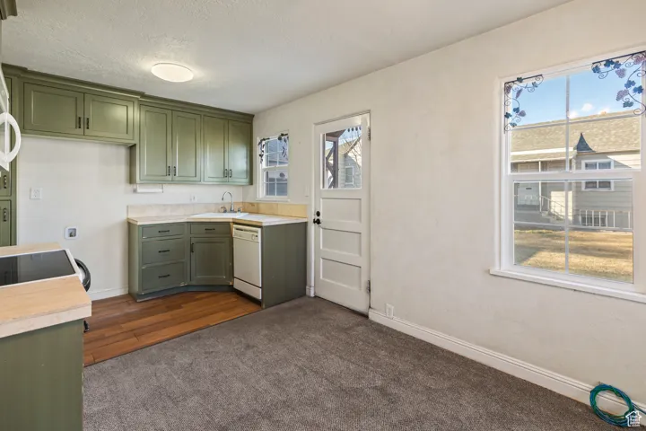 Kitchen featuring dishwasher, light countertops, plenty of natural light, and green cabinetry