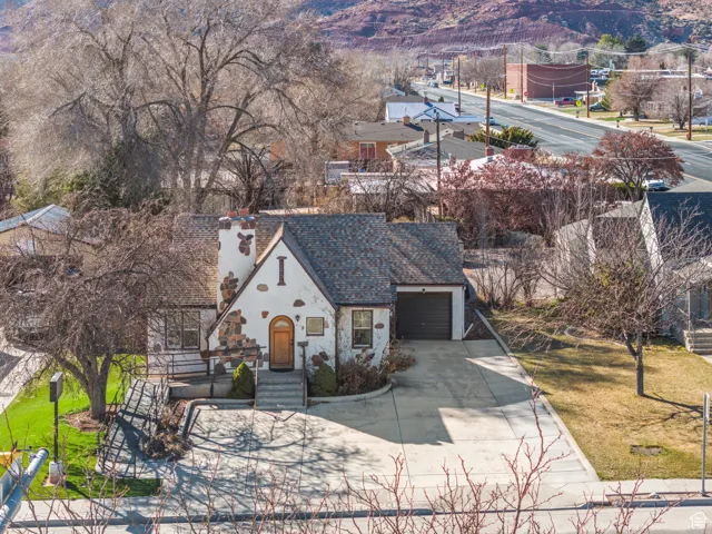 View of front of property featuring driveway, a shingled roof, stone siding, a garage, and a mountain view