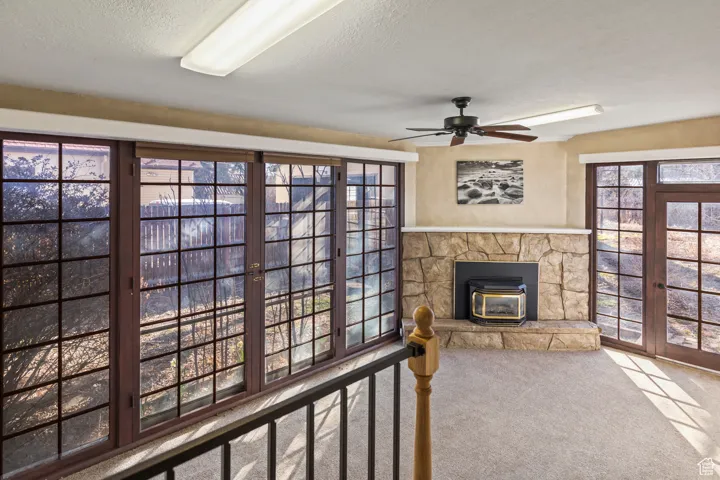 Carpeted living room with a wealth of natural light, a textured ceiling, and ceiling fan
