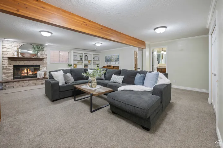 Great Room featuring a textured ceiling, a fireplace, carpet floors, and ornamental molding