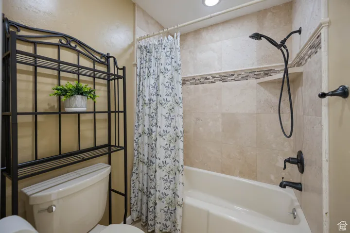 Full bathroom with shower / bathtub combination with curtain and toilet