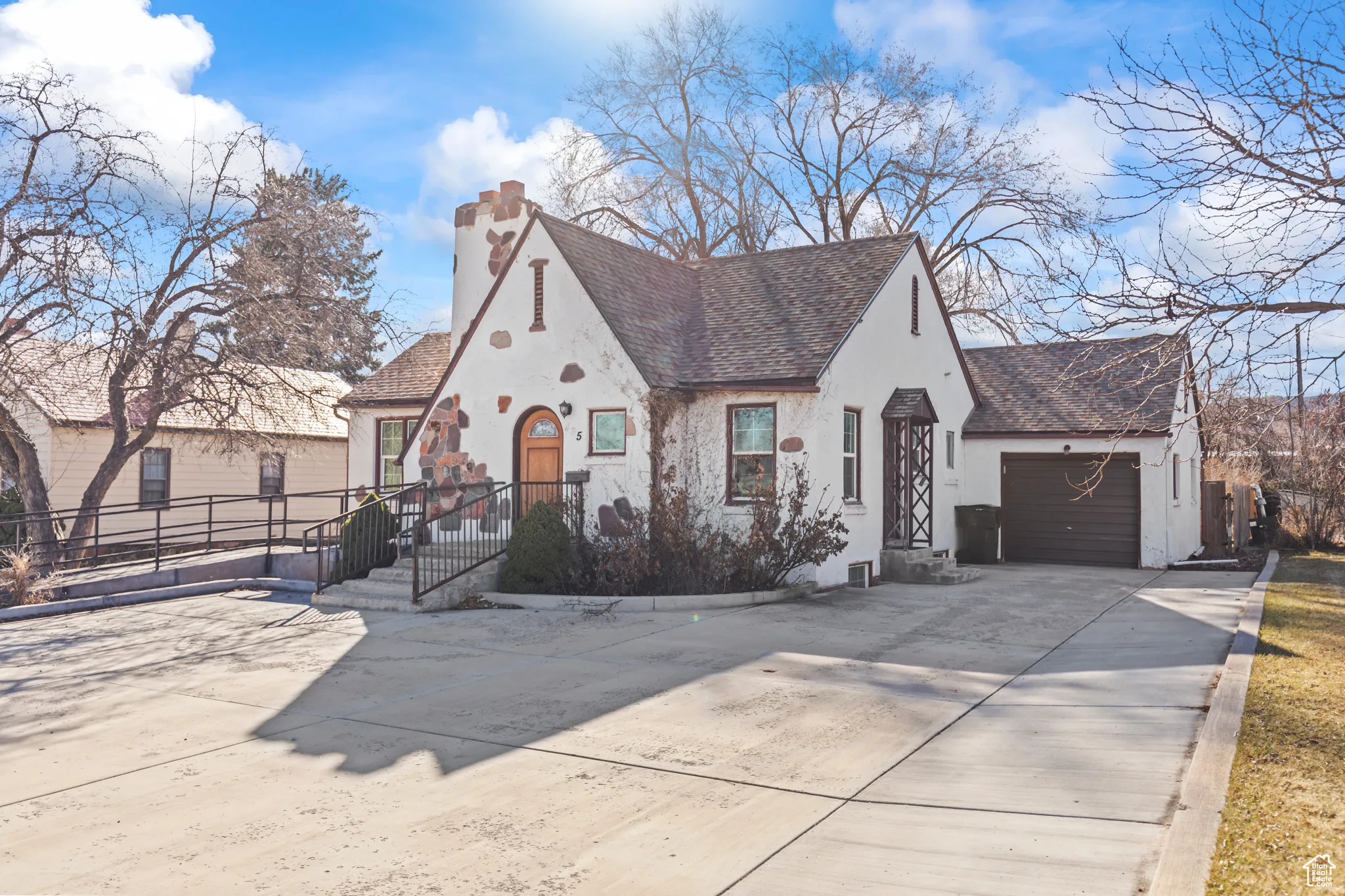 View of front of house with stucco siding, roof with shingles, concrete driveway, a garage, and a chimney