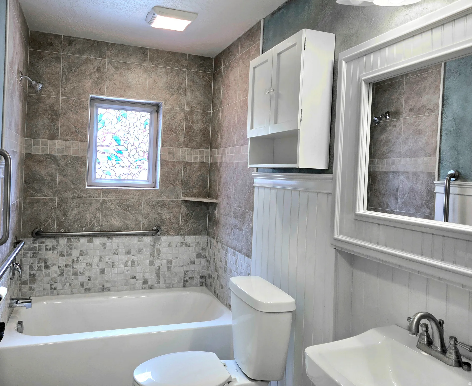 Bathroom featuring a tiled shower surround with a decorative stained-glass window