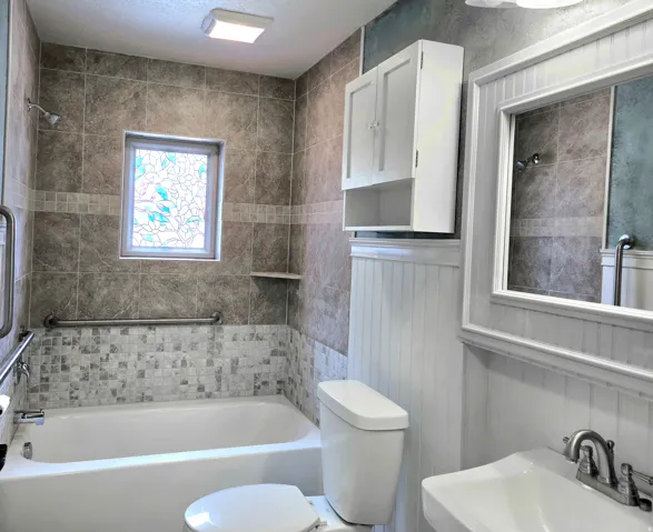 Bathroom featuring a tiled shower surround with a decorative stained-glass window