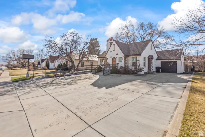 View of front facade with stucco siding, fence, concrete driveway, a garage, and a chimney