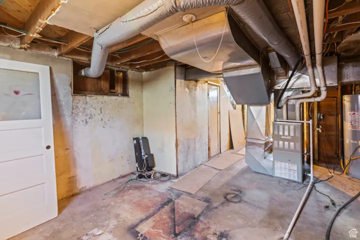 Unfinished below grade area featuring gas water heater and heating unit