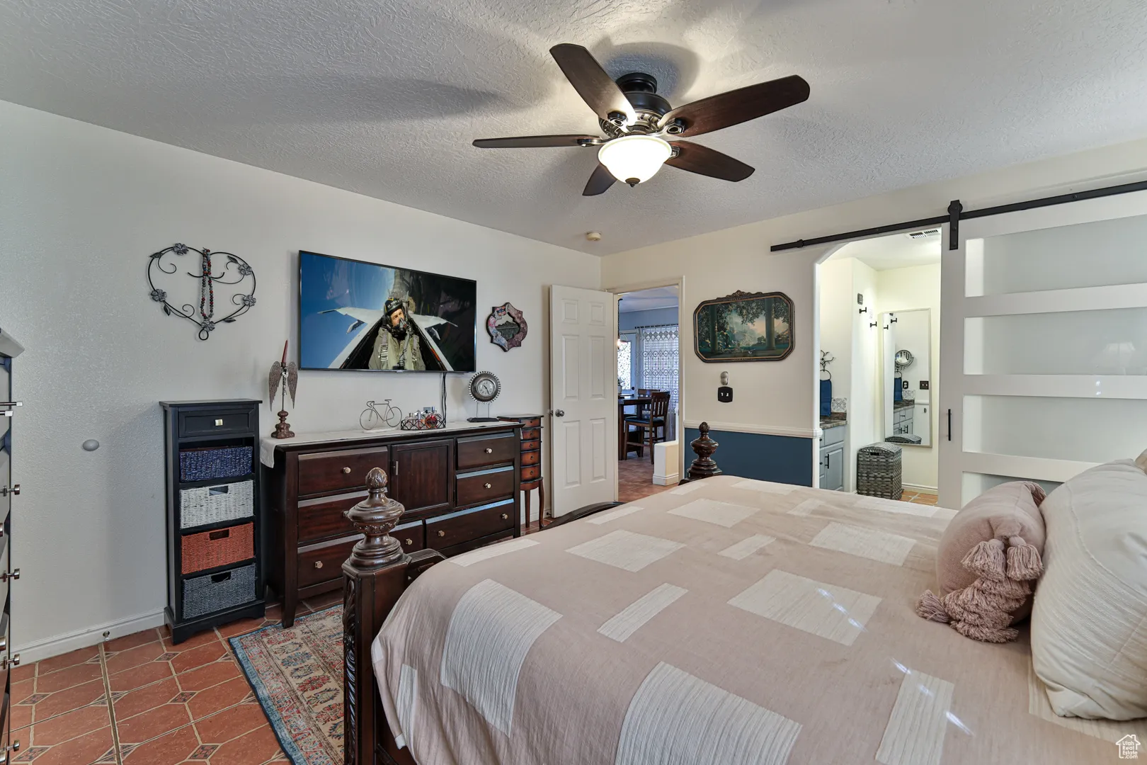 Bedroom with tile patterned flooring, ceiling fan, a textured ceiling, and a barn door