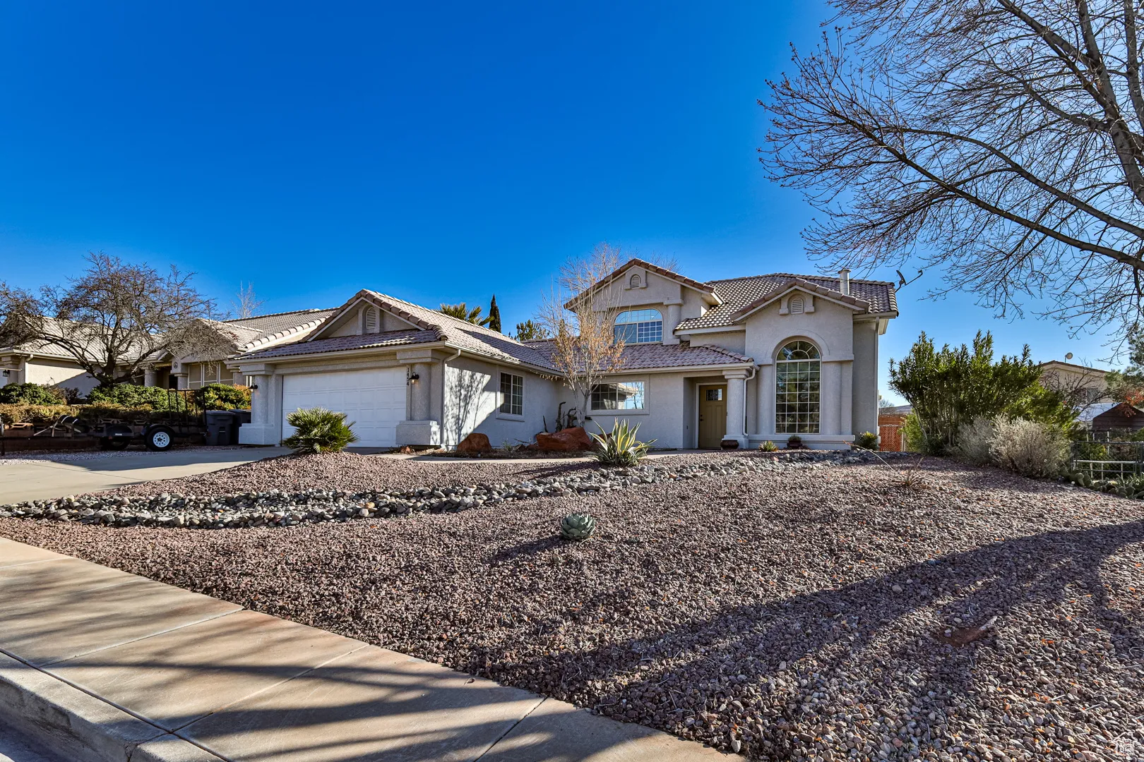 View of front of house with a tiled roof, a garage, driveway, and stucco siding