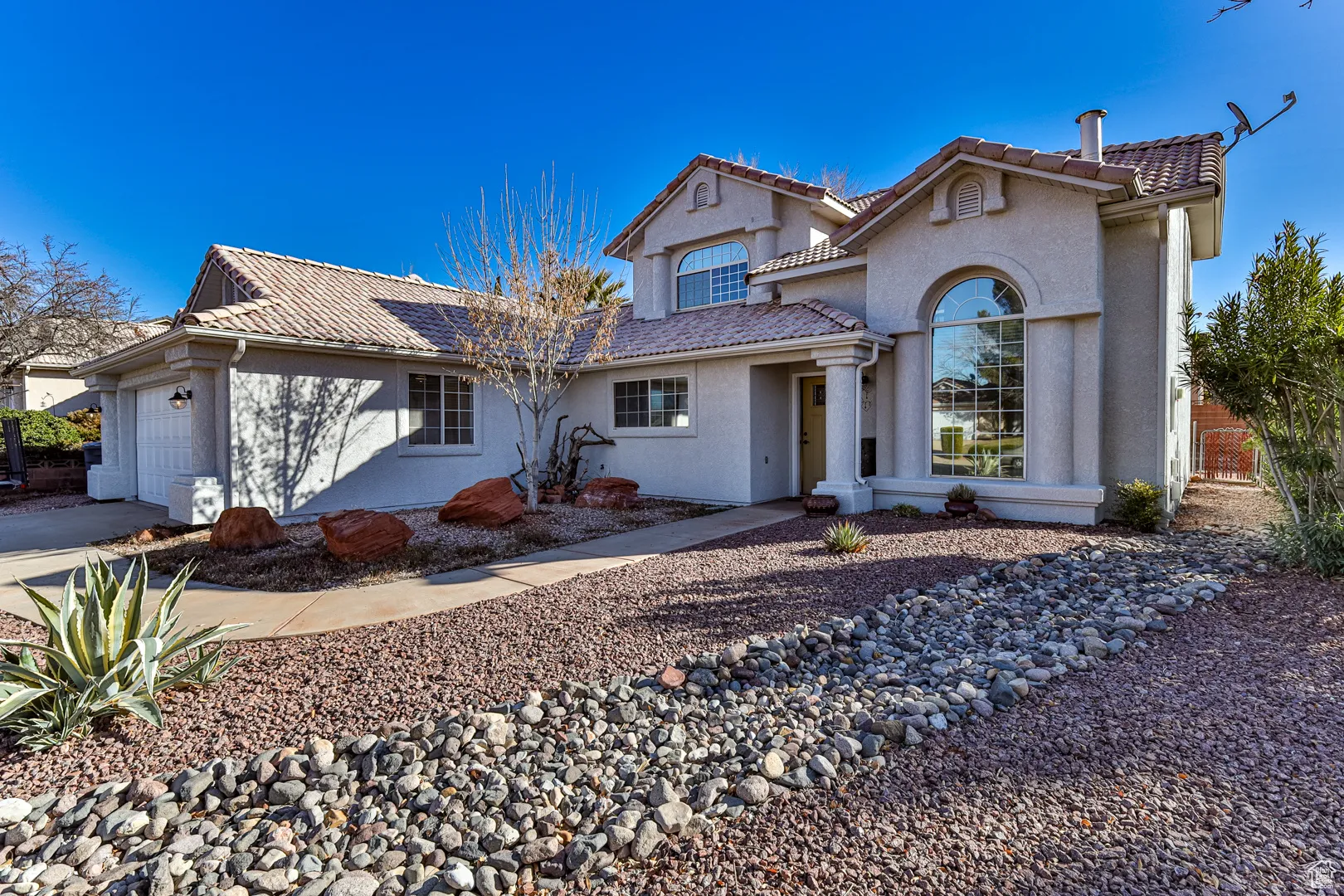 View of front of house with a tile roof, an attached garage, and stucco siding