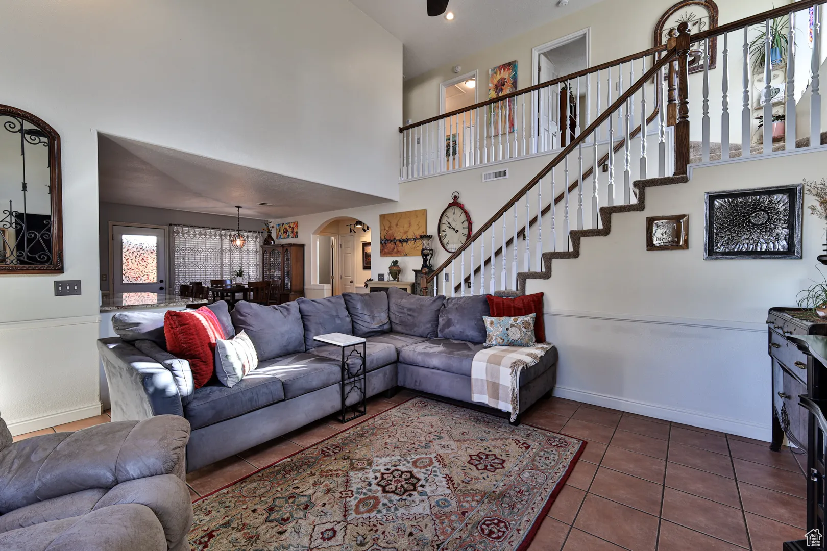 Living room featuring visible vents, stairway, arched walkways, tile patterned flooring, and baseboards