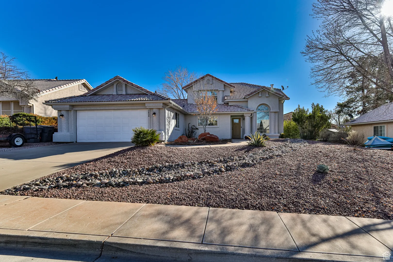 View of front of property featuring a tiled roof, a garage, driveway, and stucco siding