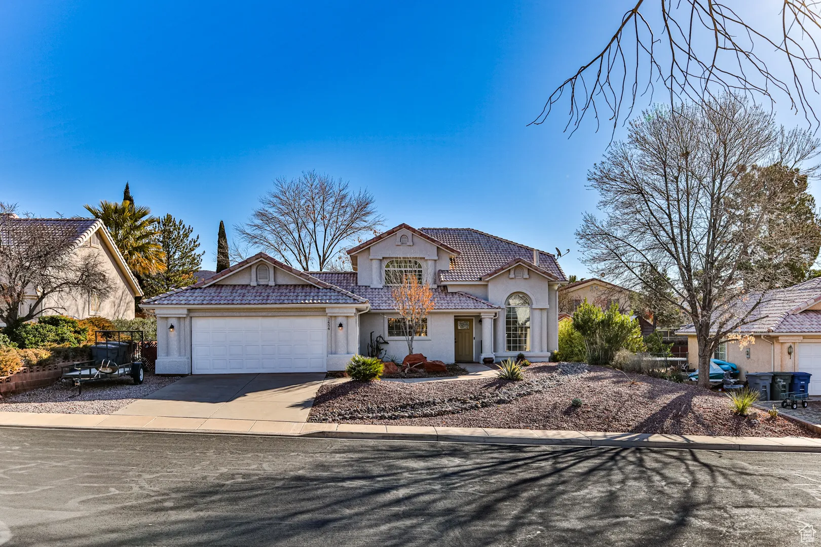View of front of property featuring stucco siding, driveway, an attached garage, and a tiled roof