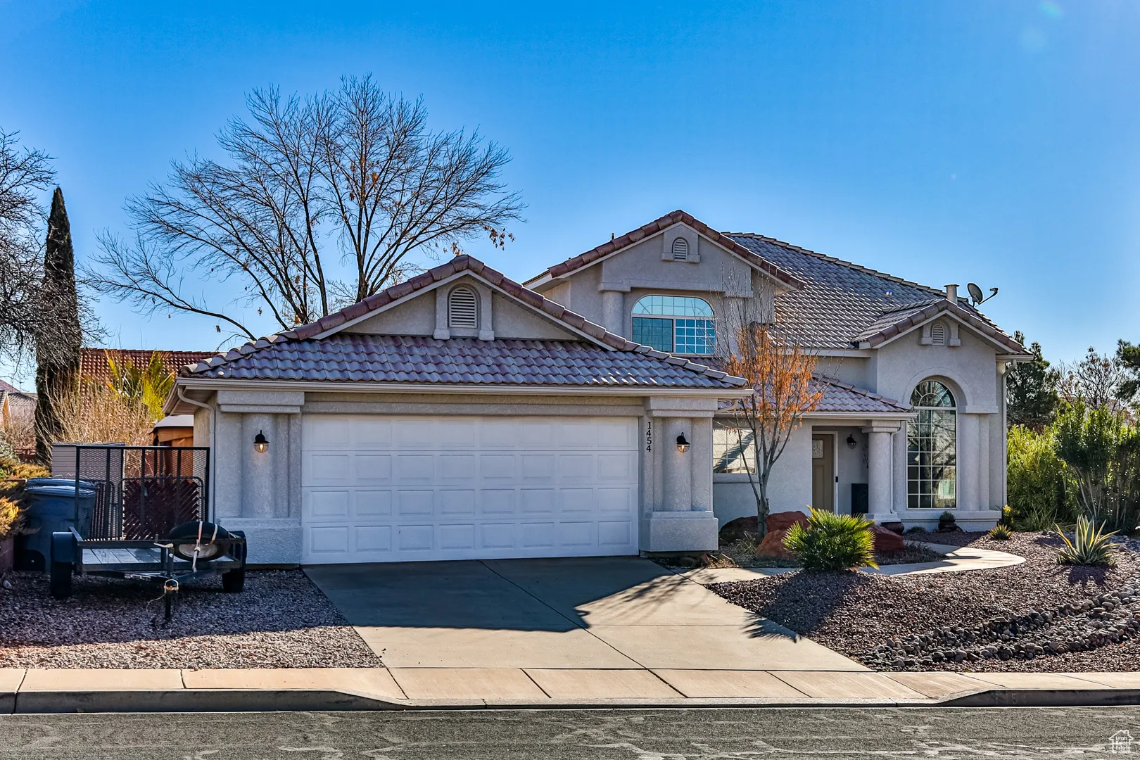 View of front facade with a tile roof, a garage, driveway, and stucco siding