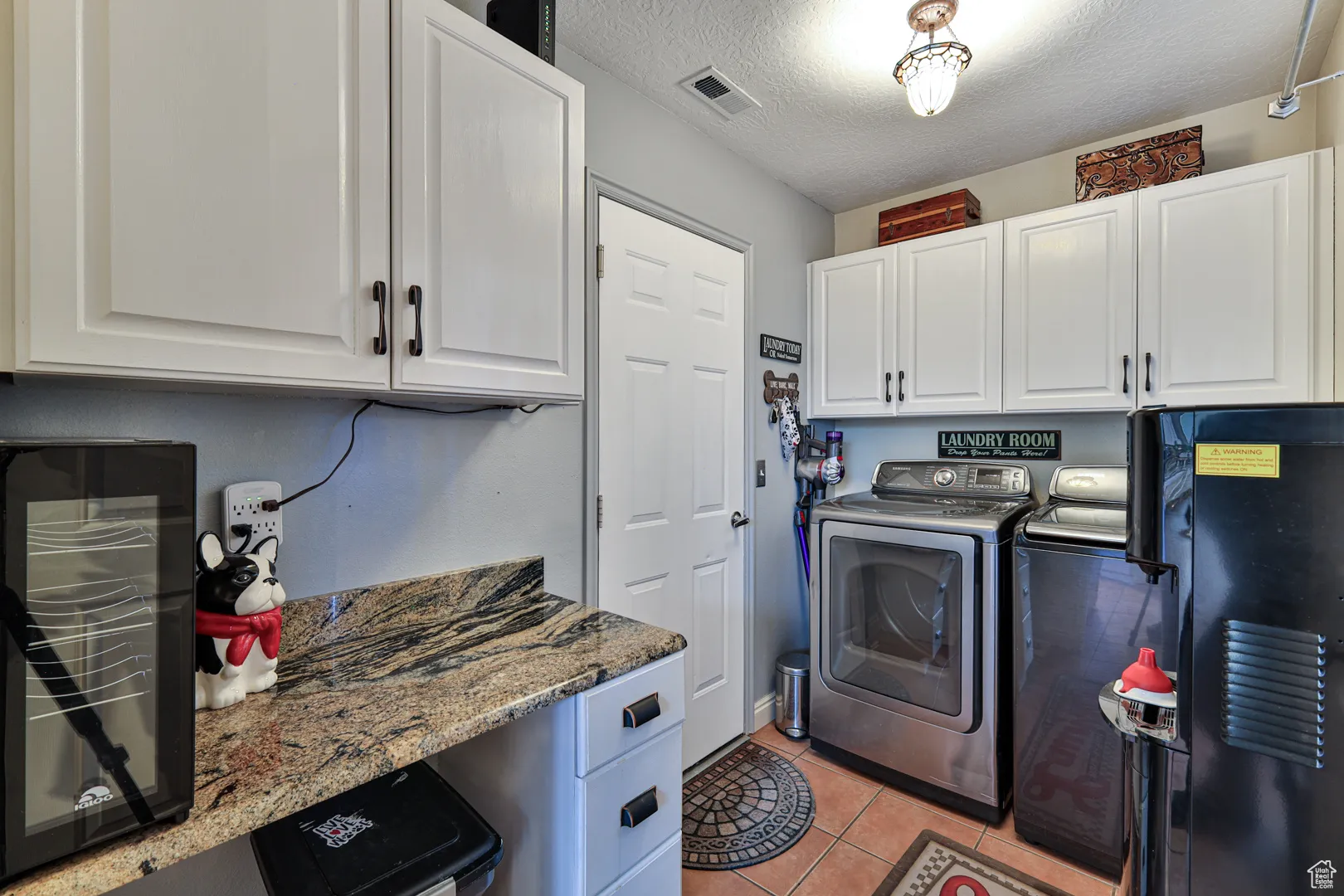 Laundry room with visible vents, washer and dryer, a textured ceiling, cabinet space, and light tile patterned floors