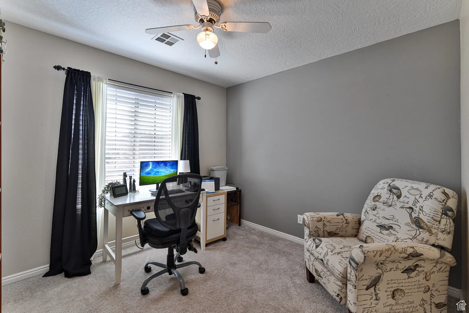 Office area with visible vents, baseboards, light colored carpet, a textured ceiling, and a ceiling fan